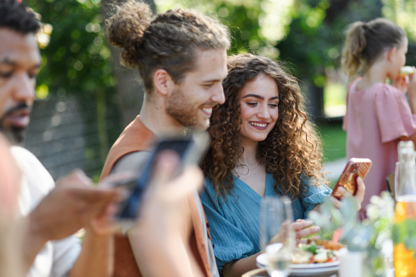 Portrait of couple sitting at the table with family and friends at the family garden party. A family gathering to celebrate a birthday.