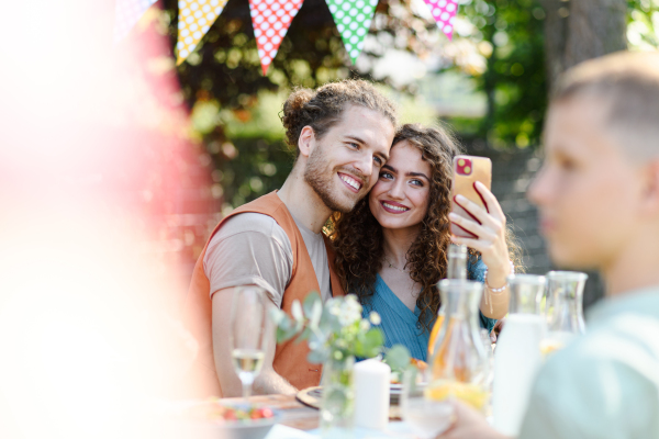 Couple taking selfie with smart phone at a summer grill garden party.