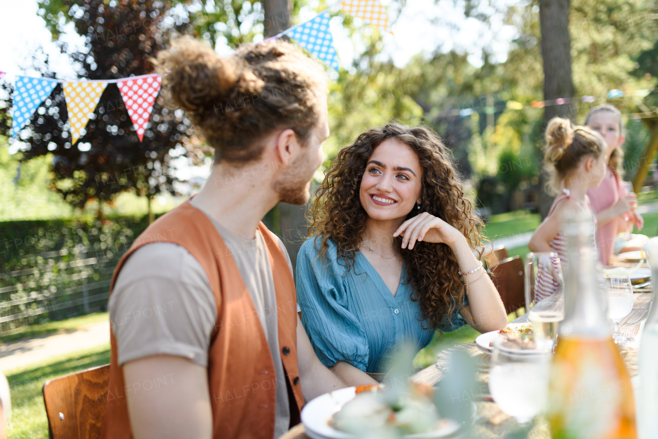 Portrait of couple sitting at the table with family and friends at the family garden party. A family gathering to celebrate a birthday.