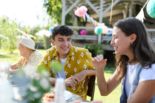 Friends chatting, laughing, and having fun at the party table during a summer garden party.