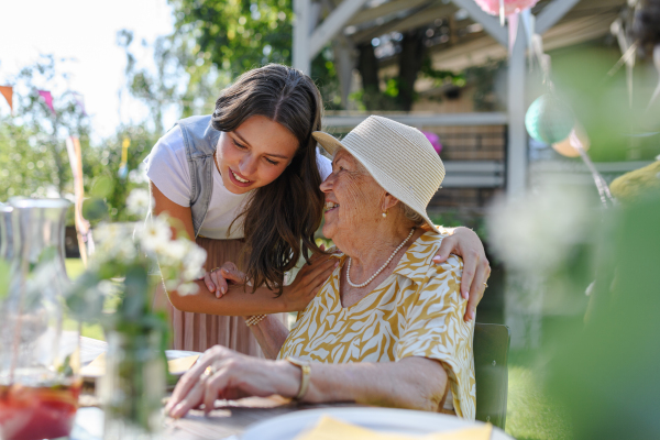 Mature granddaughter and grandmother reunite after a long time, talking and having fun. Family gathering at a garden party.