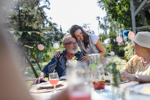 Mature granddaughter talking with grandparents, reunite after a long time. Family gathering at a garden party.