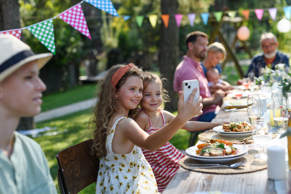 Cousins taking a selfie at a family garden party. Family reunion at a garden barbecue party.