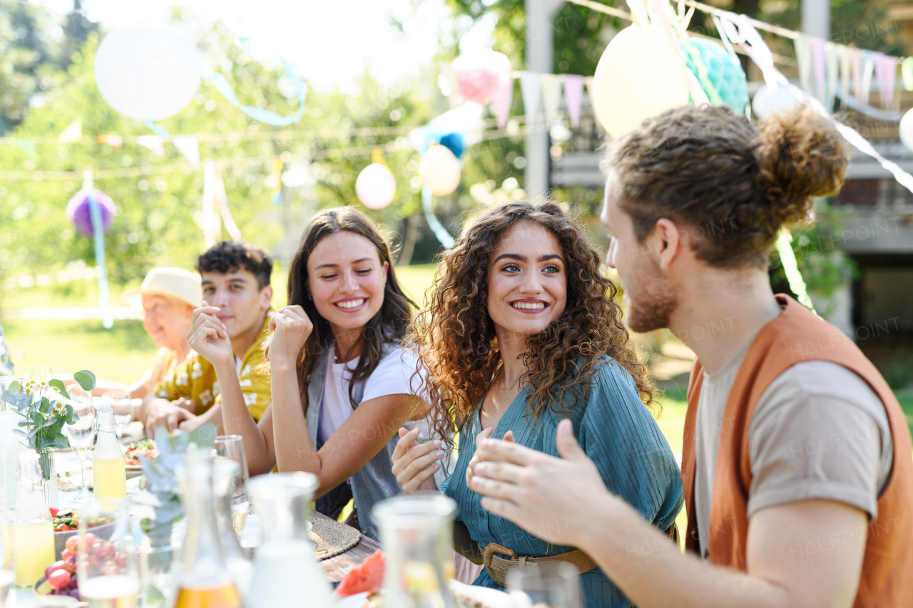 Friends chatting, laughing, and having fun at the party table during a summer garden party.