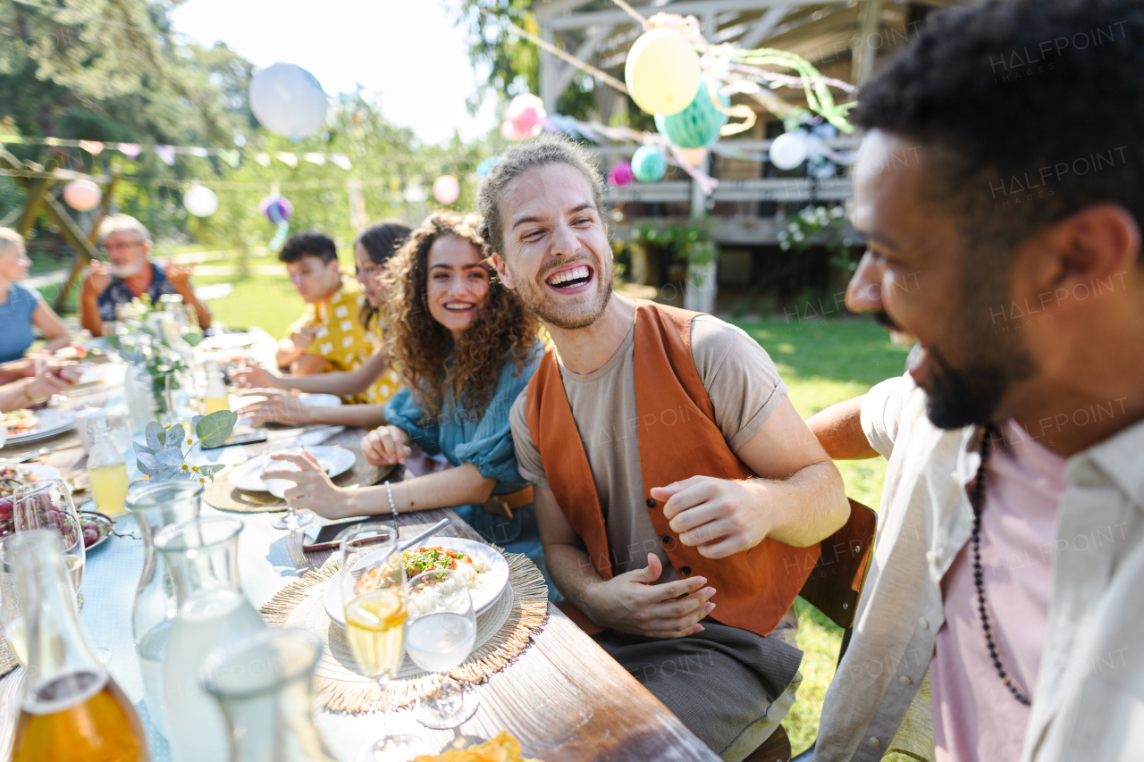 Friends chatting, laughing, and having fun at the party table during a summer garden party. Men best friends,friendship between males, bromance.