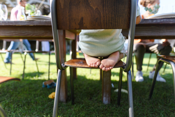 Close-up of bare children feet sticking out from a chair at a garden party.