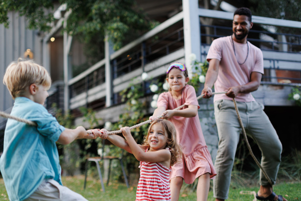 Grandparents have a tug of war with their granddaughters. Fun games at a family garden party.