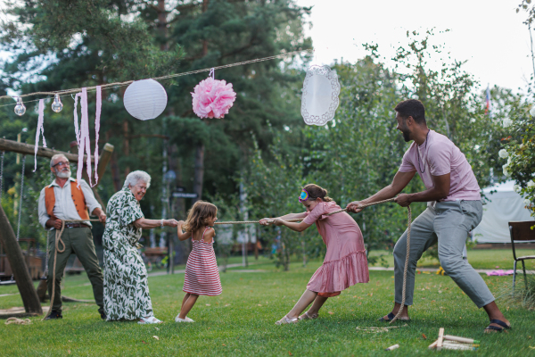 Grandparents have a tug of war with their grandchildren. Fun games at family garden party.