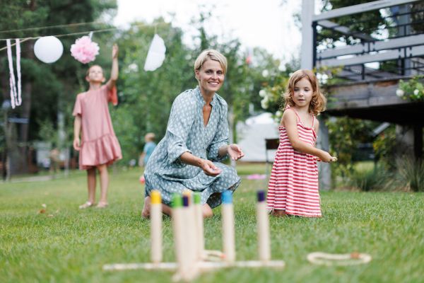 Woman playing with daughtere in the garden, outdoor garden games, sitting on grass.