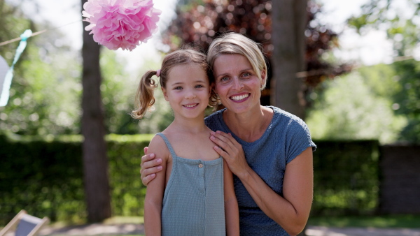 Mother and daughter posing for photo on their summer garden party.