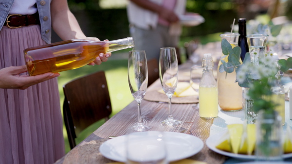 Close up video of pouring wine at summer garden party. Table setting with glasses, lemonade and bottles of summer wine.