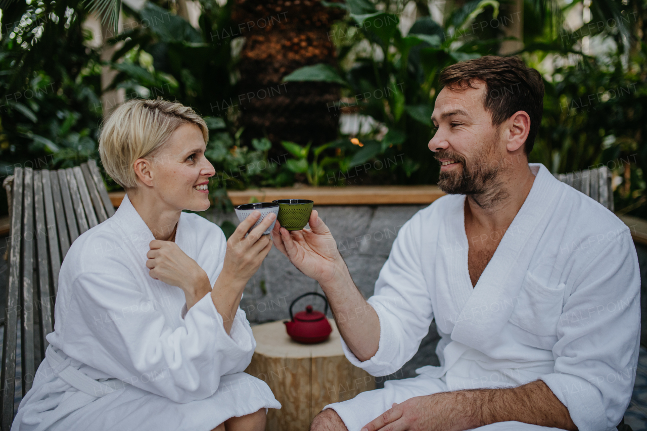 Couple in bathrobes drinking green tea, enjoying romantic wellness weekend in the spa. Concept of Valentine's Day.