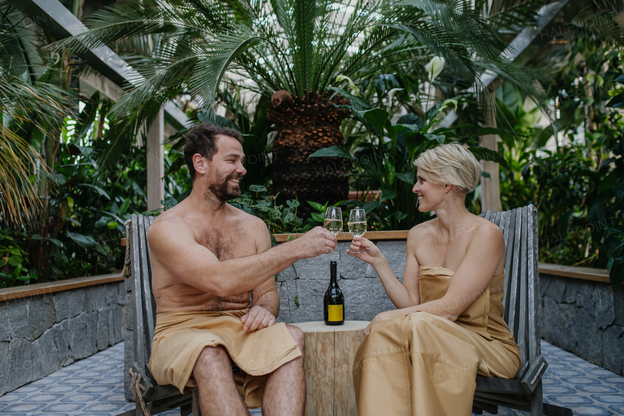 Beautiful couple standing hot tub, toasting and drinking champagne, enjoying romantic wellness weekend in spa. Concept of Valentine's Day.