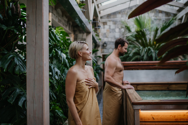 Beautiful couple standing by hot tub, enjoying romantic wellness weekend in the spa. Concept of Valentine's Day.