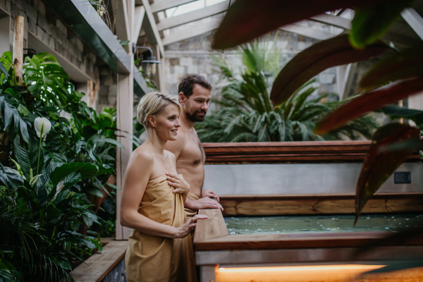 Beautiful couple standing by hot tub, enjoying romantic wellness weekend in the spa. Concept of Valentine's Day.