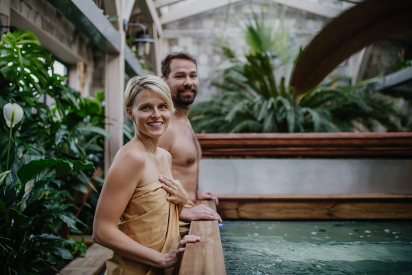 Beautiful couple standing by hot tub, enjoying romantic wellness weekend in the spa. Concept of Valentine's Day.