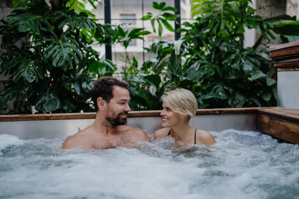 Beautiful mature couple relaxing in the hot tub, enjoying romantic wellness weekend in spa. Concept of Valentine's Day.