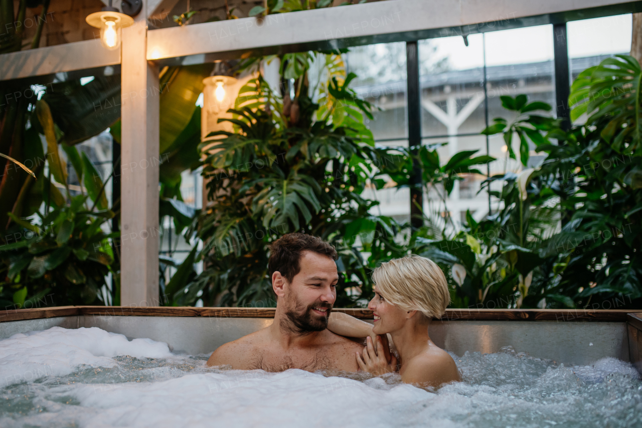 Beautiful mature couple relaxing in the hot tub, enjoying romantic wellness weekend in spa. Concept of Valentine's Day.