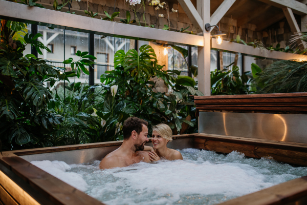 Beautiful mature couple relaxing in the hot tub, enjoying romantic wellness weekend in spa. Concept of Valentine's Day.