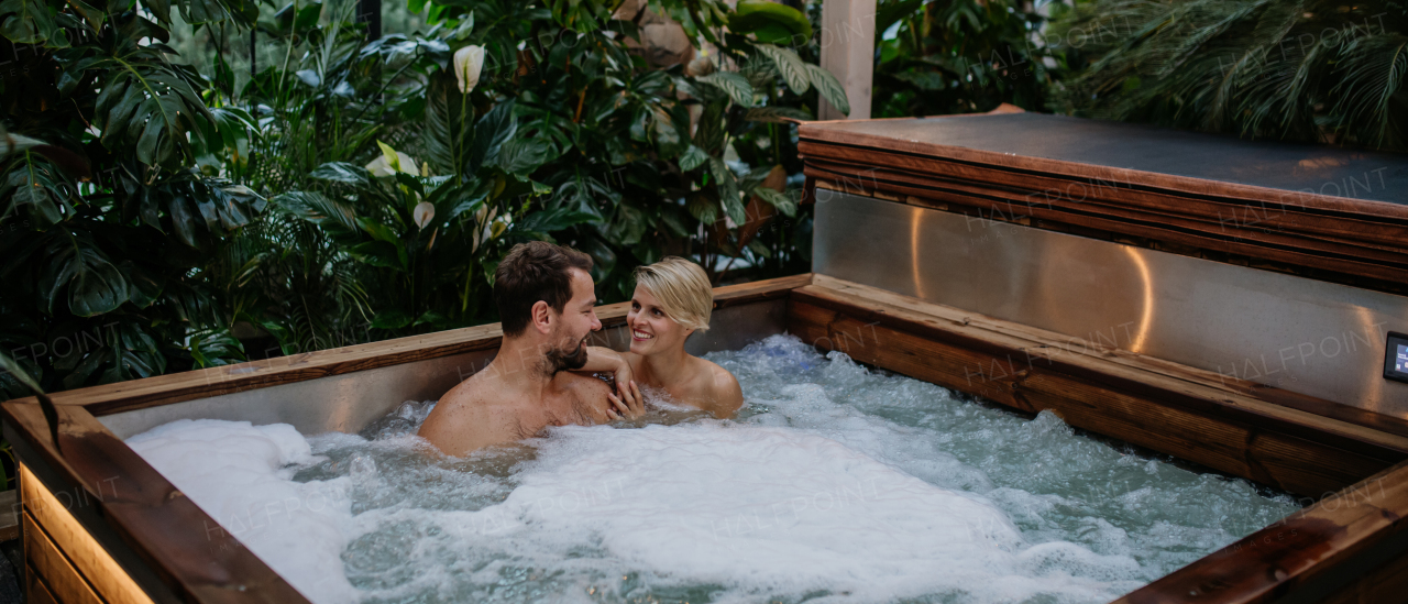 Beautiful mature couple relaxing in the hot tub, enjoying romantic wellness weekend in spa. Concept of Valentine's Day. Banner with copy space.