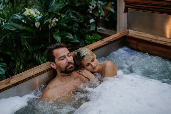 Beautiful mature couple relaxing in the hot tub, enjoying romantic wellness weekend in spa. Concept of Valentine's Day.