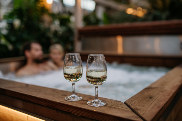 Two wine glasses on hot tub, couple relaxing, enjoying romantic wellness weekend in the spa. Concept of Valentine's Day.