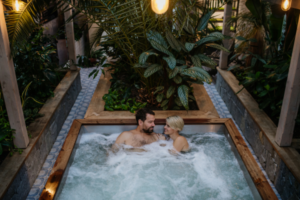 Beautiful mature couple relaxing in the hot tub, enjoying romantic wellness weekend in spa. Concept of Valentine's Day.