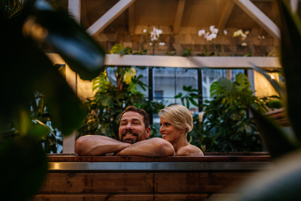 Beautiful mature couple relaxing in the hot tub, enjoying romantic wellness weekend in spa. Concept of Valentine's Day.