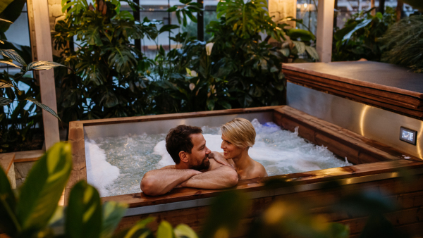 Beautiful mature couple relaxing in the hot tub, enjoying romantic wellness weekend in spa. Concept of Valentine's Day.