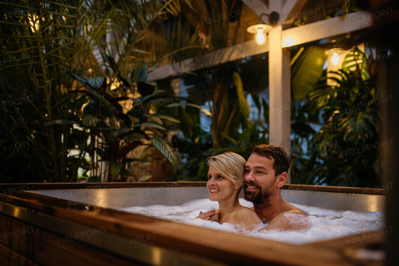 Beautiful mature couple relaxing in the hot tub, enjoying romantic wellness weekend in spa. Concept of Valentine's Day.