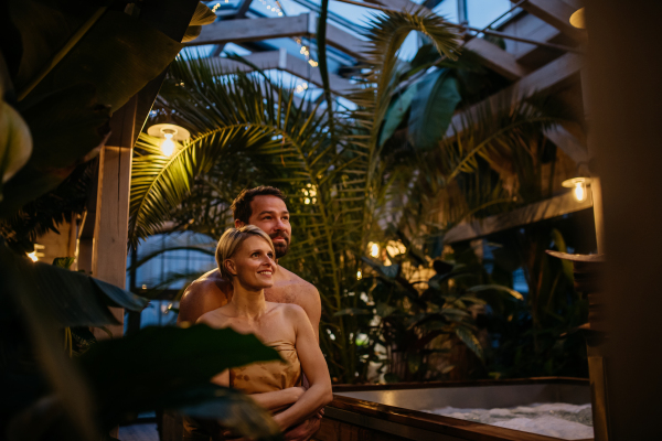 Beautiful couple standing in hotel greenhouse, enjoying romantic wellness weekend in the spa. Concept of Valentine's Day.