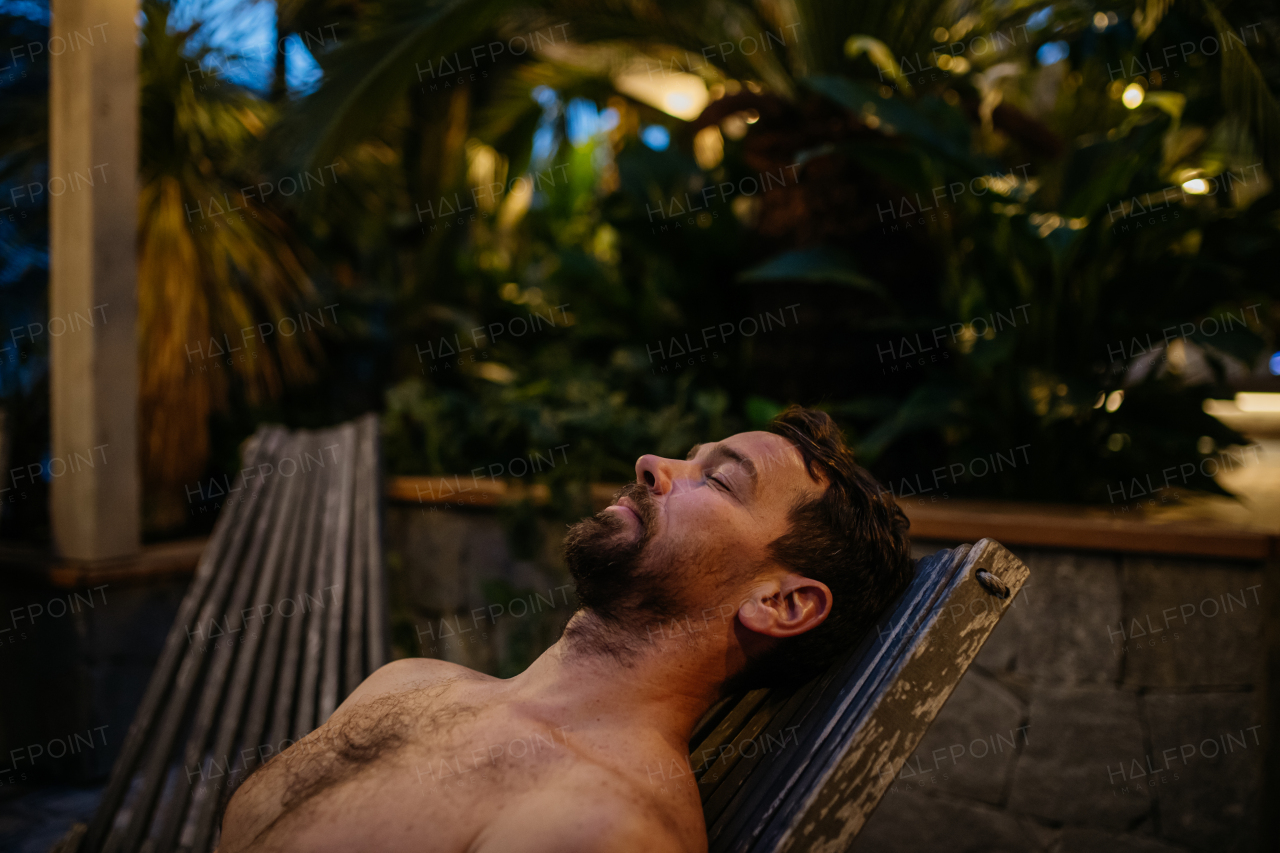 Handsome man lying on recliner, relaxing with closed eyes, enjoying alone time. Wellness weekend in spa for man.