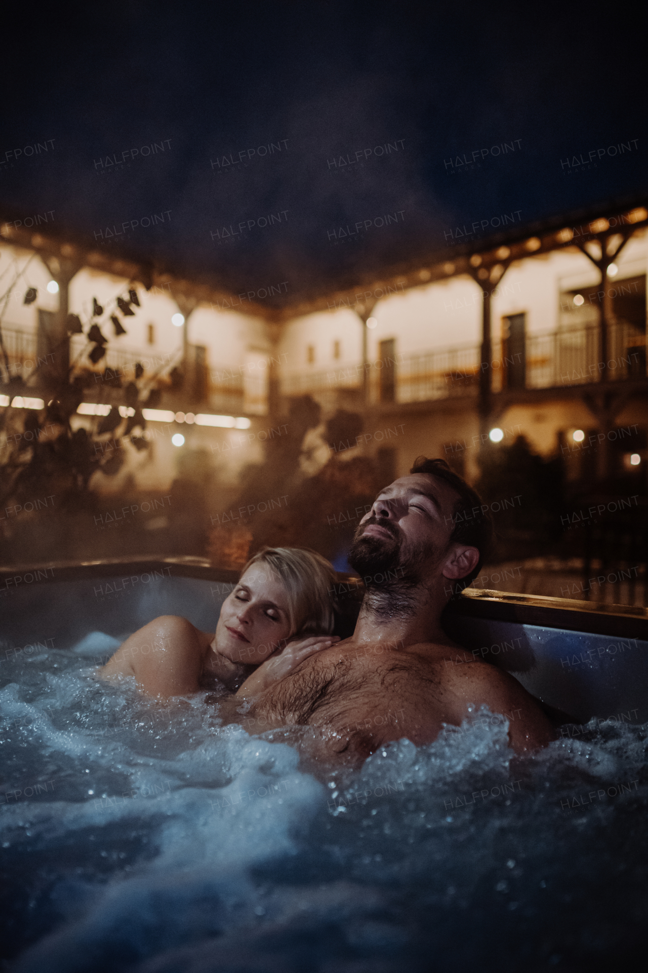 Beautiful mature couple relaxing in outdoor hot tub, enjoying romantic wellness weekend in the spa. Concept of Valentine's Day.