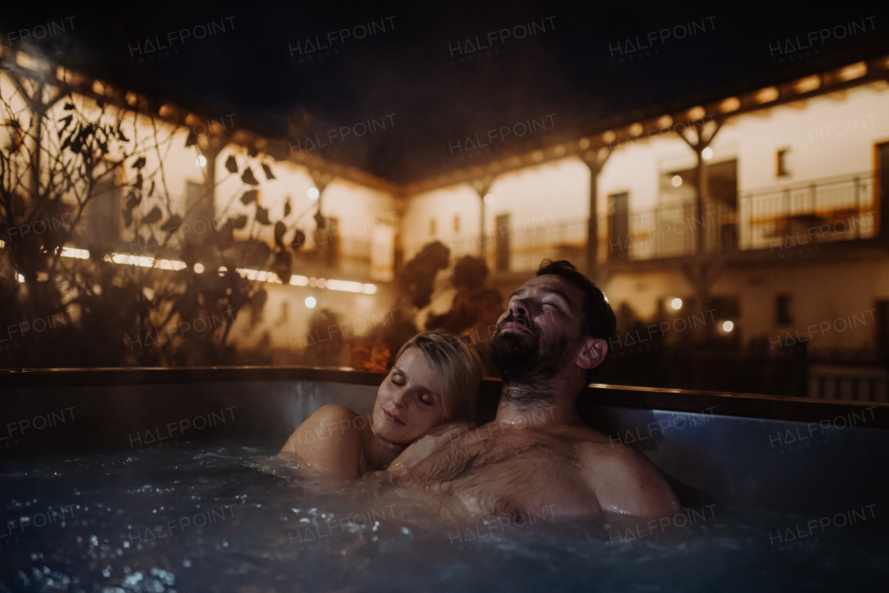 Beautiful mature couple relaxing in outdoor hot tub, enjoying romantic wellness weekend in the spa. Concept of Valentine's Day.