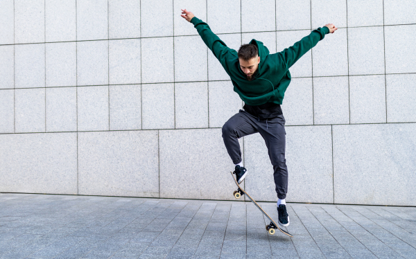 Young man skating outdoors in the city. Stylish skateboarder training in skate park. Concept of skateboarding as sport and lifestyle.