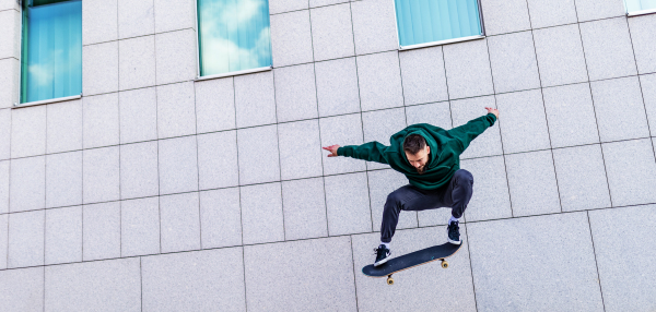 Young man skating outdoors in the city. Stylish skateboarder training in skate park. Concept of skateboarding as sport and lifestyle.