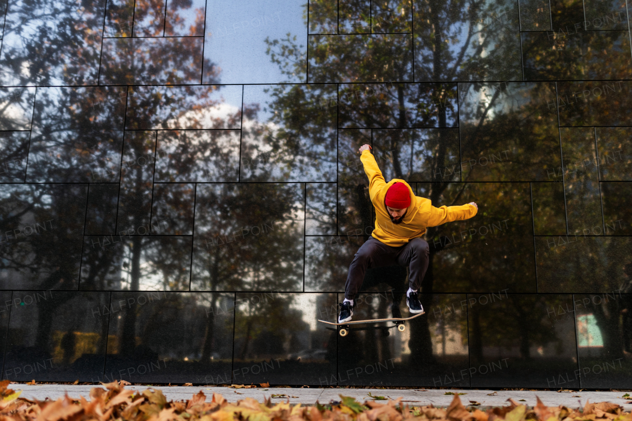 Skateboarder man skating in city, jumping, ollie jump. Stylish skateboarder training in skate park. Concept of skateboarding as sport and lifestyle.