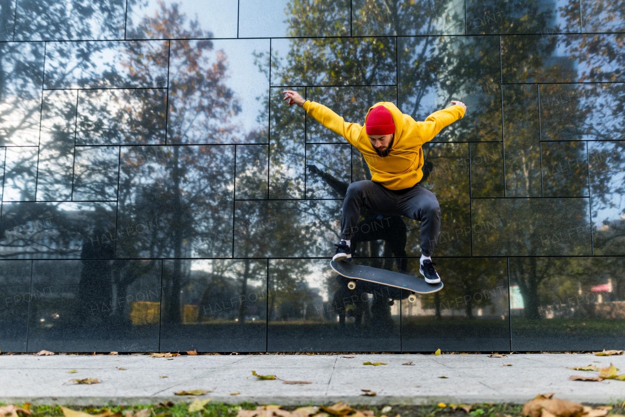 Young man skating outdoors in the city. Stylish skateboarder training in skate park. Concept of skateboarding as sport and lifestyle.