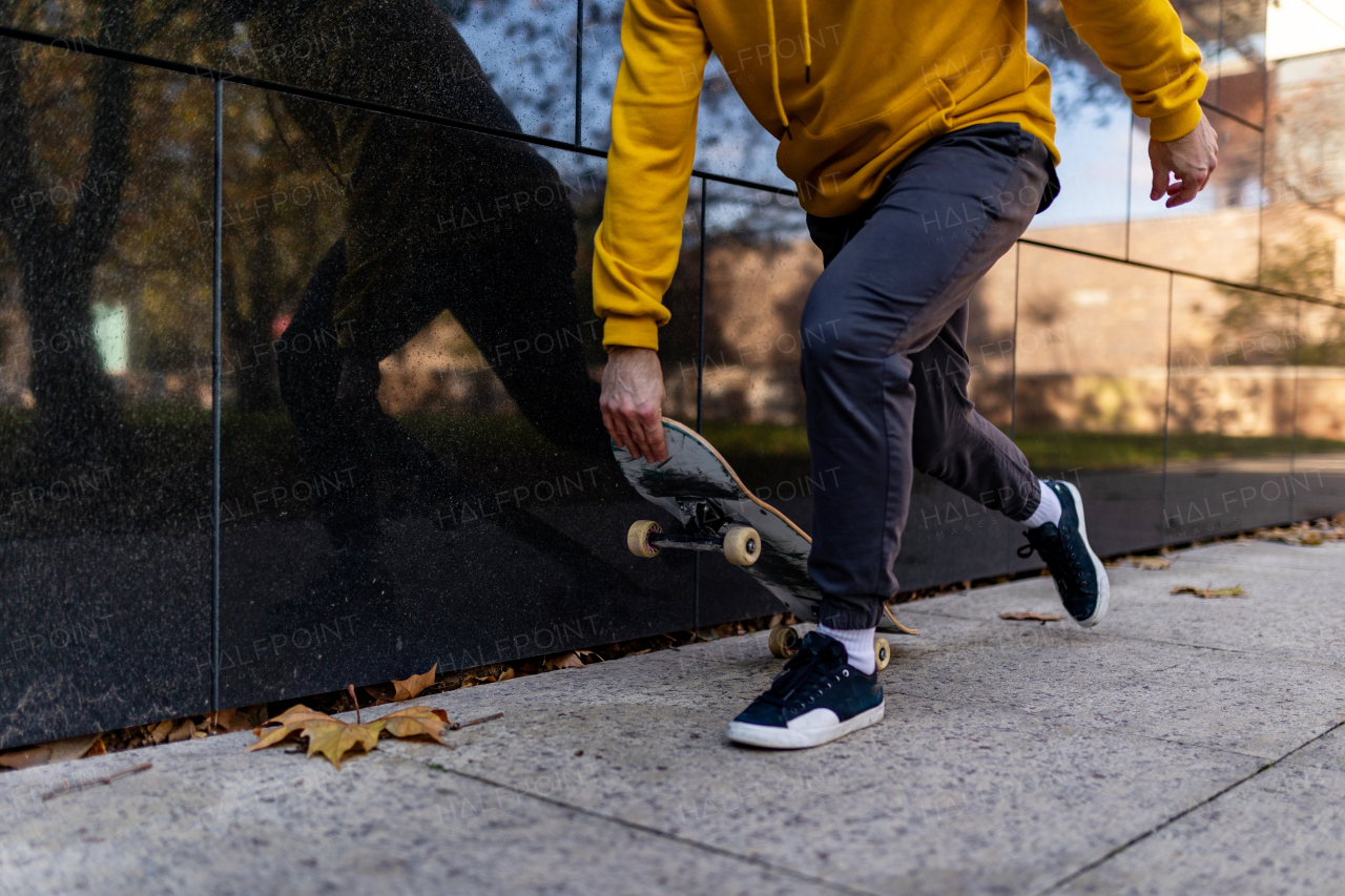 Close up on legs and skateboard of man skating in the city. Stylish skateboarder training in skate park. Concept of skateboarding as sport and lifestyle.