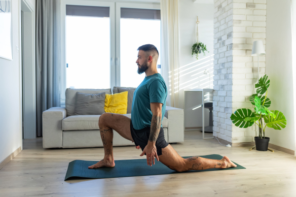 Handsome man doing yoga, stretching, resting after home workout, New Year's resolutions, exercising as healthy lifestyle and selfcare. Concept of morning or evening workout routine.