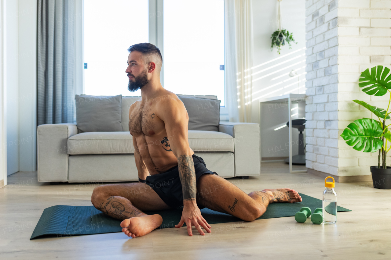 Handsome man doing yoga, stretching, resting after home workout, New Year's resolutions, exercising as healthy lifestyle and selfcare. Concept of morning or evening workout routine.