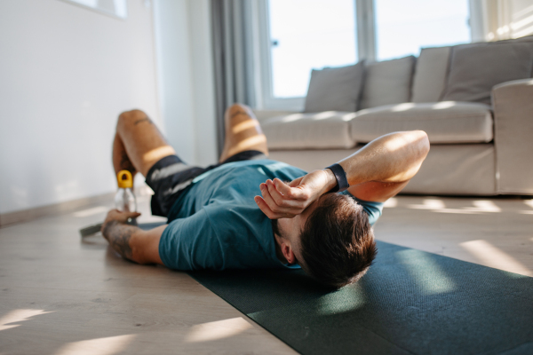 Young man resting after home workout, New Year's resolutions, exercising as healthy lifestyle and selfcare. Concept of morning or evening workout routine.