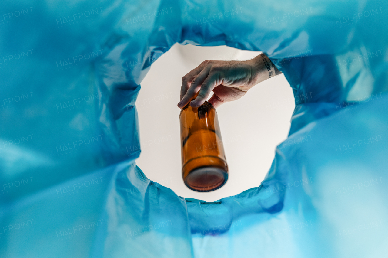 Man throwing glass bottle into recycling bin. Throwing empty alcohol bottle, New Year's resolutions, drink less alcohol healthy lifestyle without alcoholic drinks.