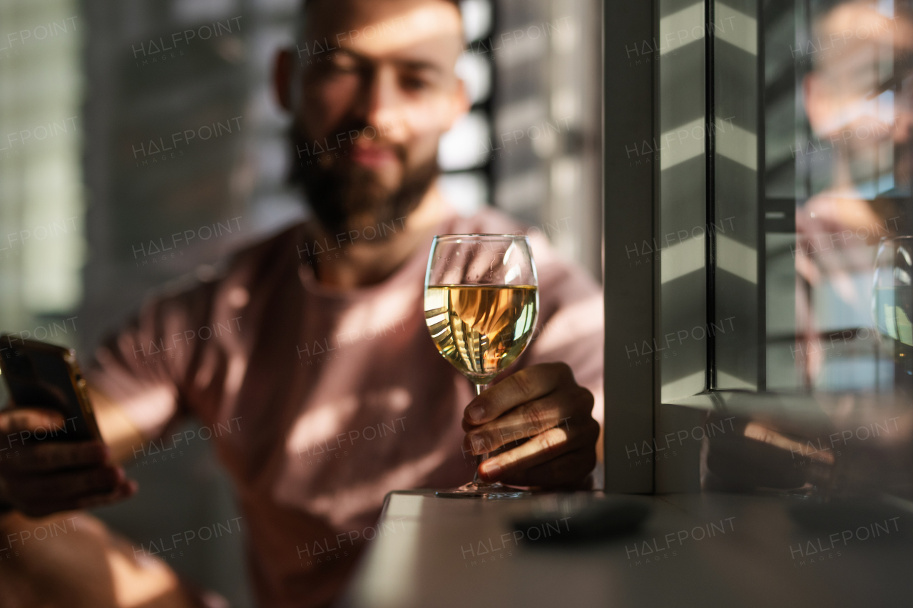 Young man looking at a glass with white wine, New Year's resolutions, drink less alcohol healthy lifestyle without alcoholic drinks.