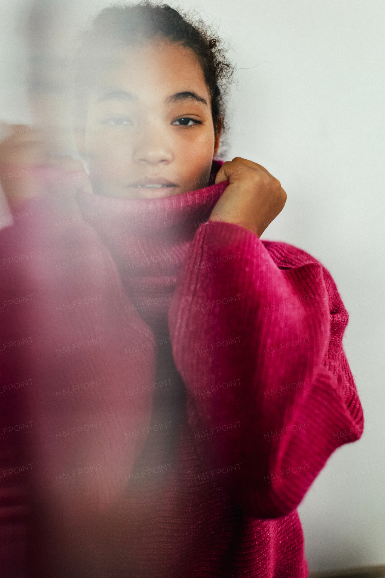 Portrait of beautiful curvy woman holding collar of pink turtleneck sweater, looking at camera.