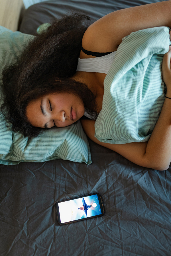 Woman using mobile meditation app to help sleep better at night. Concept of sleep routine. Insomnia a sleep problems among adults.