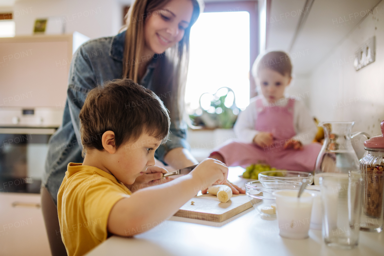 A mother of two little children preparing breakfast in kitchen at home.