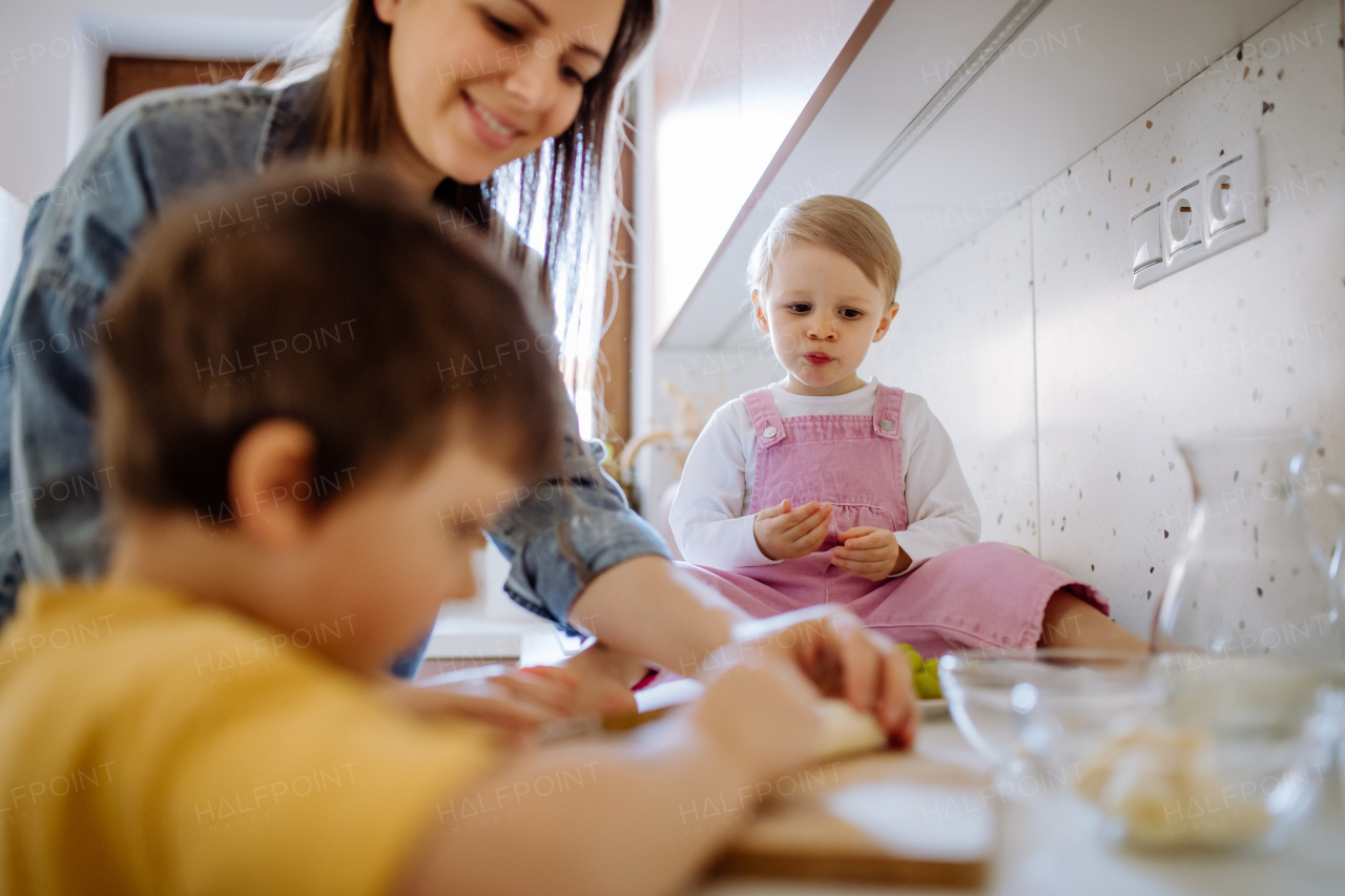 A mother of two little children preparing breakfast in kitchen at home.