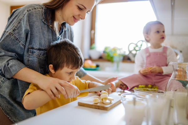 A mother of two little children preparing breakfast in kitchen at home.