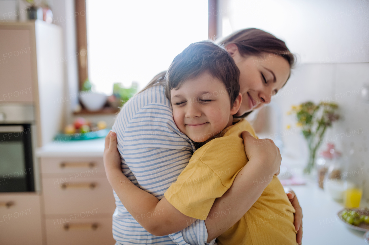 A happy oung mother hugging her little son in kitchen at home.